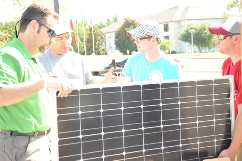Daniel Tate, center, of the Alabama Center for Sustainable Energy, Raul Alonso, left and Dominic Ragucci, right, U.S. Army Engineering and Support Center, Huntsville help volunteer assemble solar panel August 8.