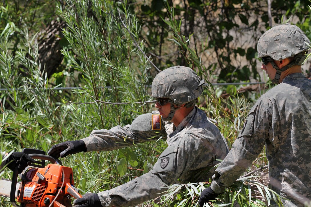 California Army National Guardsmen operate a chainsaw to remove debris