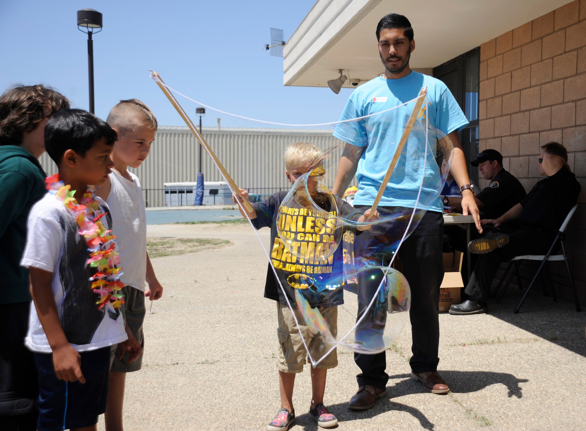 A volunteer teaches children how to use a bubble wand at the Salute to Youth event, Aug. 7, 2015, Vandenberg Air Force Base, Calif. More than 40 Team V volunteers ensured the success of the day’s events – manning a rock climbing wall, making balloon animals and preparing food for those in attendance. (U.S. Air Force photo by Airman 1st Class Robert J. Volio/Released)