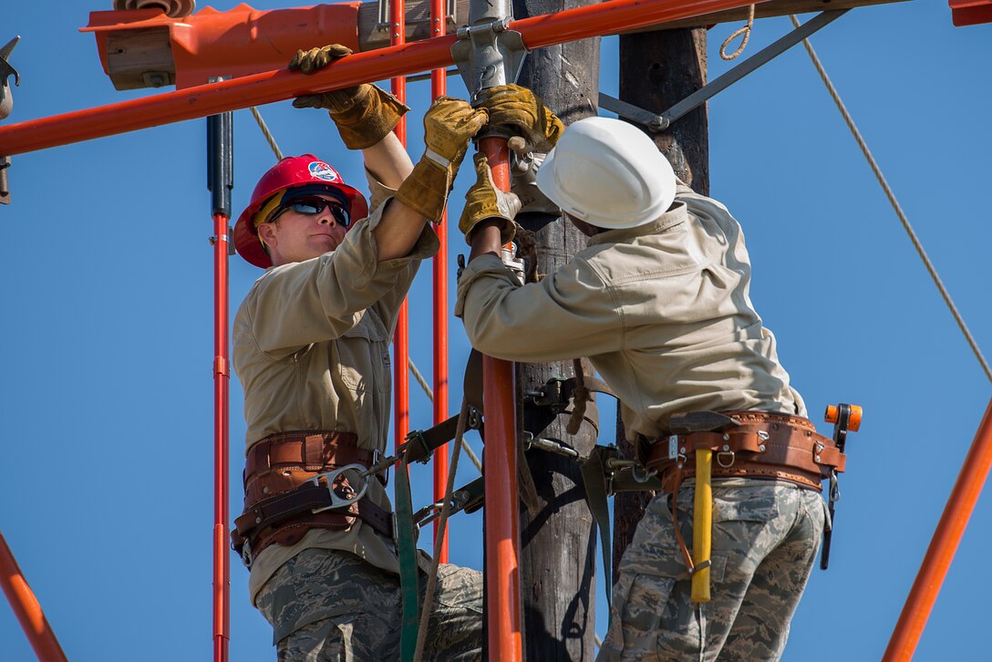U.S. Air Force Staff Sgt. Andrew Goodrick, (left), from Nellis Air Force Base Nev., is a student in the 366th Training Squadron Hotline Training Course and native of Lawrence Kan., trains with Airman 1st Class Jaylen Wilkens, (right), from Charleston Air Force Base S.C., who is also a student in the course and native of Pittsburg Pa., at Sheppard Air Force Base, Texas, Aug. 7, 2015. The Hotline Training Course teaches the students how to safely manage electrified power lines in a controlled training environment. Airmen in this course wear a modified uniform to protect themselves from the various equipment and chemicals they use. (U.S. Air Force photo by Senior Airman Kyle Gese/Released)