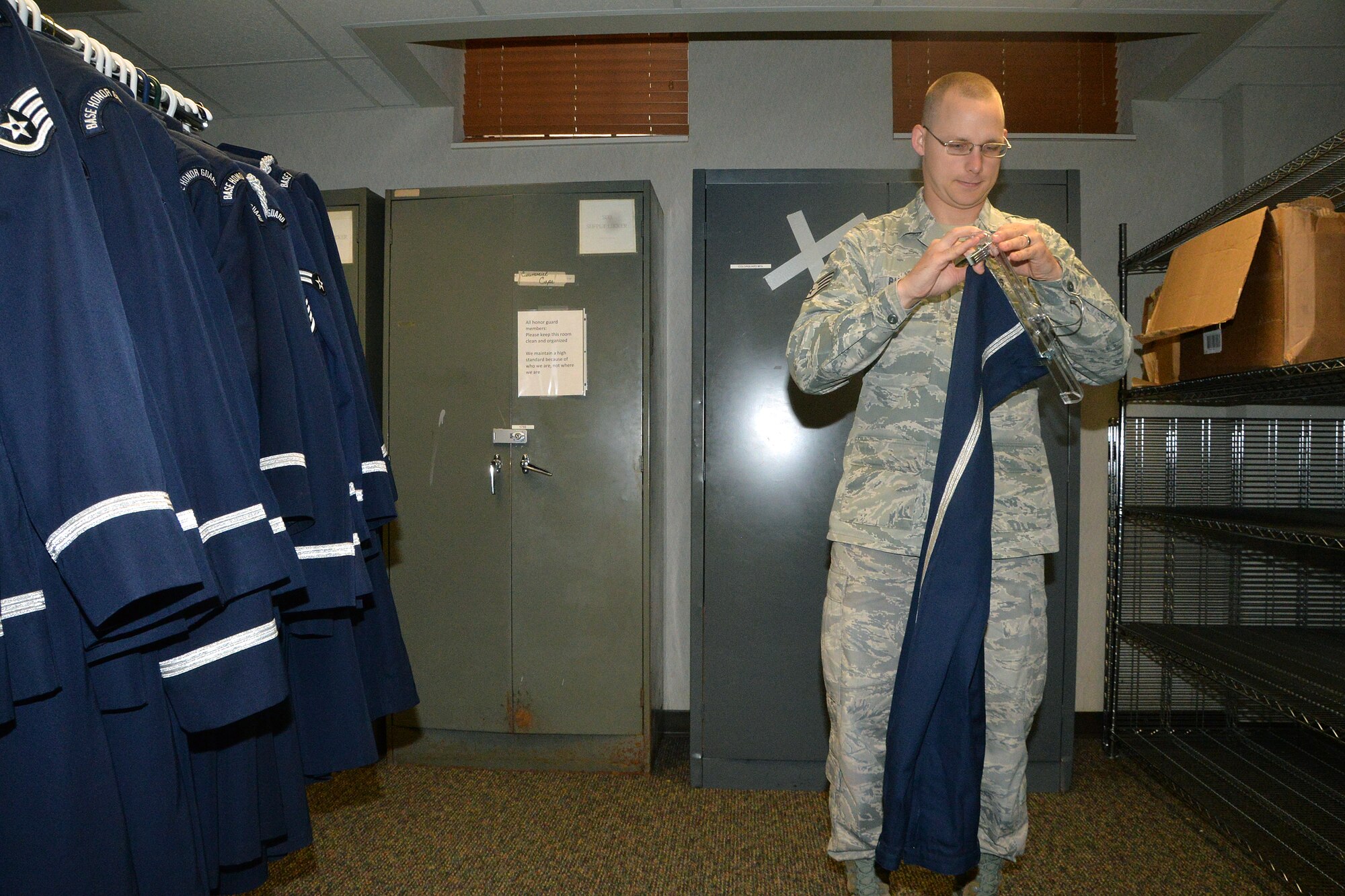 U.S. Air Force Staff Sgt. Christopher Burke’s, 55th Wing Honor Guard NCO in charge, hangs a pair of Honor Guard uniform pants Aug. 7 at Offutt Air Force Base, Nebraska. Burke collects uniforms from outgoing honor guard Airmen in order to pass them down to incoming guardsmen. (U.S. Air Force photo by Dana P. Heard)