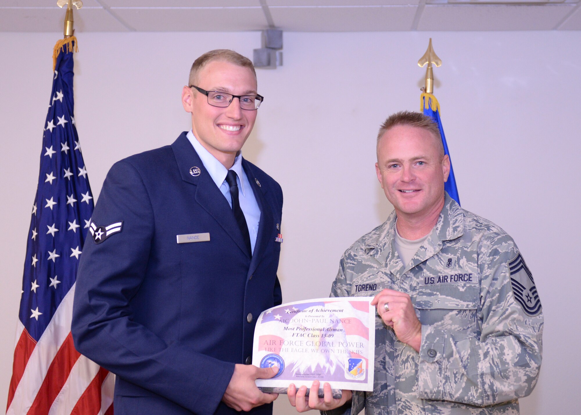 Chief Master Sgt. Michael Toreno, 49th Medical Group superintendent, presents Airman 1st Class John-Paul Nance, from the 49th Aeromedical Squadron, with the Most Professional Airman Award at the First Term Airman Course Class 15-09 graduation. FTAC is a program that helps first term airmen with the transition from technical school to an operational environment. It also gives the airmen a warm welcome to Holloman from the majority of base agencies they will be working with on a daily basis. (U.S. Air Force photo by Staff Sgt. E’Lysia A. Wray)