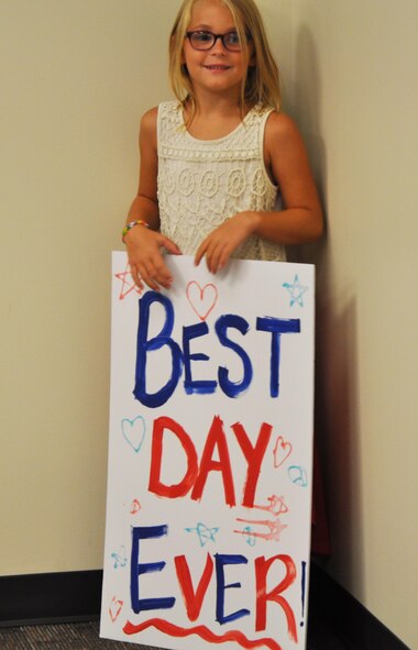 The daughter of Senior Airman Derek McLaren, 931st Aircraft Maintenance Squadron maintainer, holds a handmade sign as she awaits the return of her father, Aug. 10, 2015, at McConnell Air Force Base, Kan. Approximately ten members of the 931st Air Refueling Group returned after a deployment to Southwest Asia. (U.S. Air Force photo by Tech. Sgt. Abigail Klein)