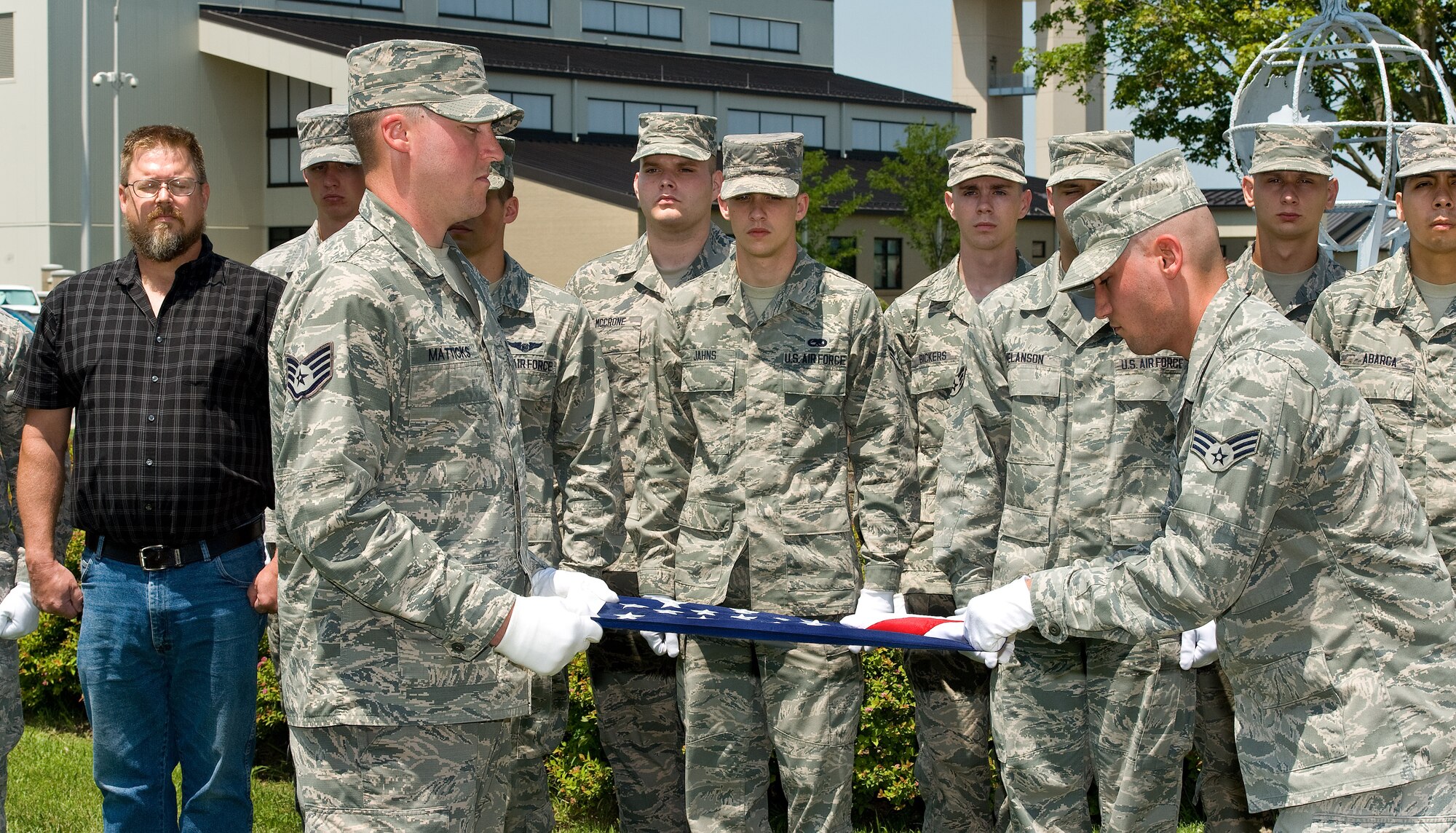 Staff Sgt. Joshua Matticks, left, and Senior Airman Michael Russo, right, both members of the Dover Air Force Base Honor Guard fold a U.S. flag July 17, 2015, at the base flagpole on Dover AFB, Del. Master Sgt. (ret.) Wayne Garvine, left, asked the Honor Guard to properly fold the flag that was flown on a July 2005 combat rescue mission to recover the remains of U.S. Navy SEAL Petty Officer 2nd Class Matthew Axelson. (U.S. Air Force photo/Roland Balik)