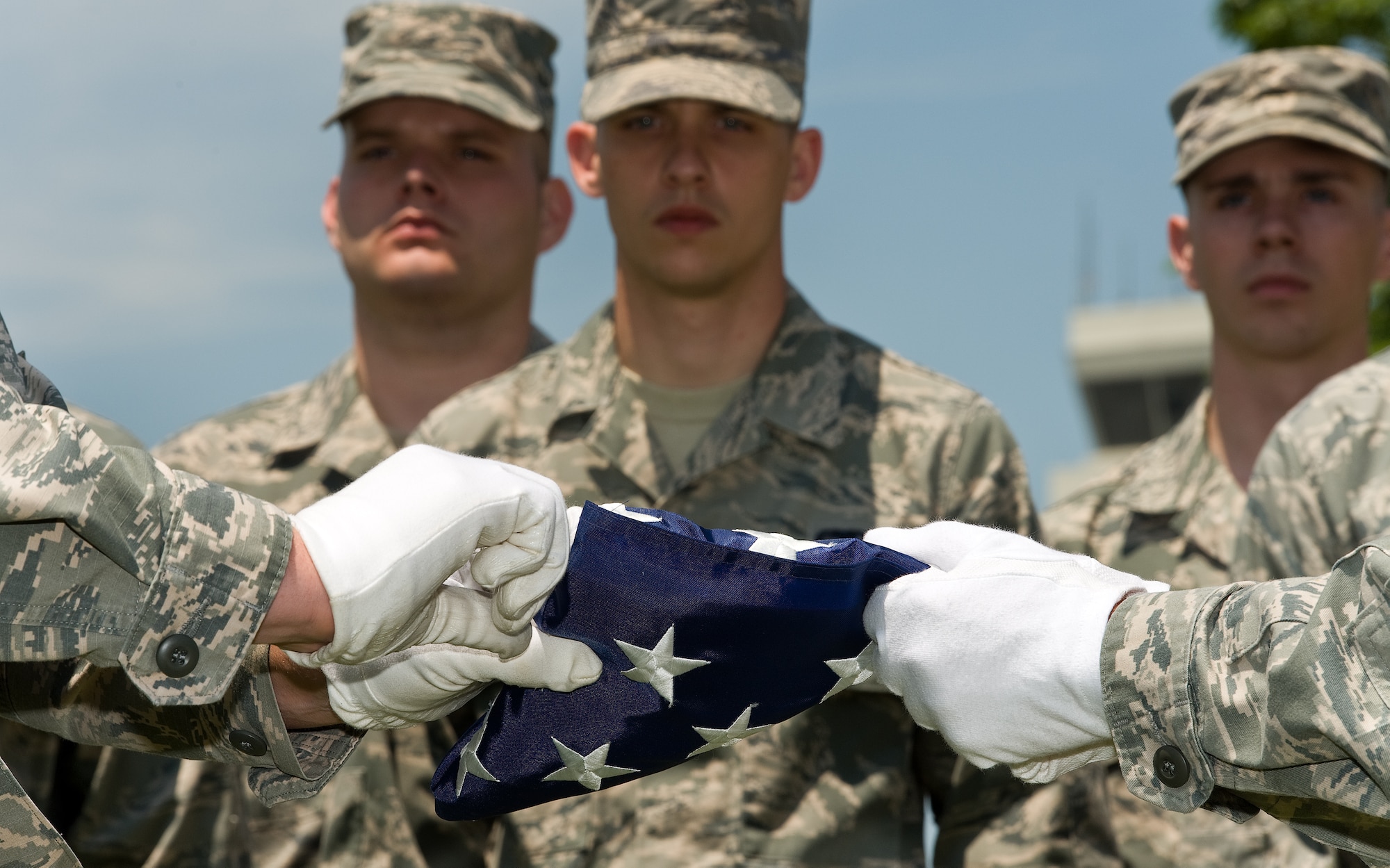 Members of the Dover Air Force Base Honor Guard observe the U.S. flag being folded on July 17, 2015, at the base flagpole on Dover AFB, Del. Staff Sgt. Joshua Matticks and Senior Airman Michael Russo, both members of the Dover Air Force Base Honor Guard, folded the flag for former 436th Communications Squadron land mobile radio technician Master Sgt. (ret.) Wayne Garvine. The flag was flown on a combat rescue mission conducted by a 59th Expeditionary Rescue Squadron aircrew tasked to recover the remains of U.S. Navy SEAL Petty Officer 2nd Class Matthew Axelson, July 10, 2005. (U.S. Air Force photo/Roland Balik)