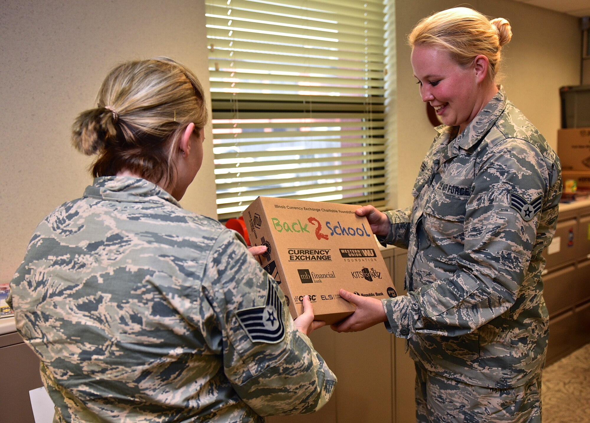 Senior Airman Ashley Albers, a material management clerk with the 932nd Logistics Readiness Flight, is handed an age specific back to school kit from Tech. Sgt. Roxanne Wood, Non-Commissioned Officer in Charge with the 932nd Airlift Wing Airman and Family Readiness section.  Various school supplies and pre-made kits are donated by Operation Home Front as a way to help ease expenses for Airmen and their families.  Albers has two school age children and they continue to use items from the kits they received last year. "I think this is very beneficial and my oldest loves to draw with the included paper," Albers said. (U.S. Air Force photo/Tech. Sgt. Christopher Parr)
