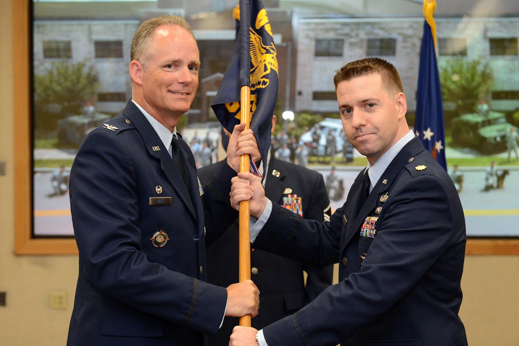 Col. Michael A. Vogel, 66th Air Base Group commander, passes the 66th Security Forces Squadron guidon to Maj. Joseph Bincarusky Sr. during a change of command ceremony at the Hanscom Conference Center Aug. 7. Bincarusky replaces Lt. Col. Michael Morales as 66 SFS commander. (U.S. Air Force photo by Jerry Saslav)