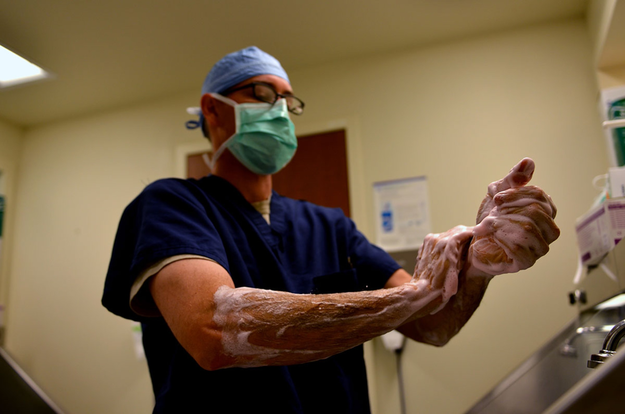 Air Force Maj. Justin Clark, a 673d Medical Group general surgeon, scrubs in for surgery July 27 outside an operating room in the Joint Base Elmendorf-Richardson hospital. The operating rooms are clean areas and everyone must wear scrubs, foot covers, hair covers, and masks while in the room to ensure the area remains sterile. 
 (U.S. Air Force photo/Airman 1st Class Kyle Johnson)
