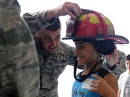 Staff Sgt. Jacob Butitta, 22nd Civil Engineer Squadron fire protection crew chief, places a helmet on a child during the annual “Big for a Day” event, Aug. 6, 2015, at McConnell Air Force Base, Kan. The event allowed children from the local community to learn about different jobs in the Air Force and spend time with McConnell Airmen. (U.S. Air Force photo by Airman 1st Class Tara Fadenrecht)