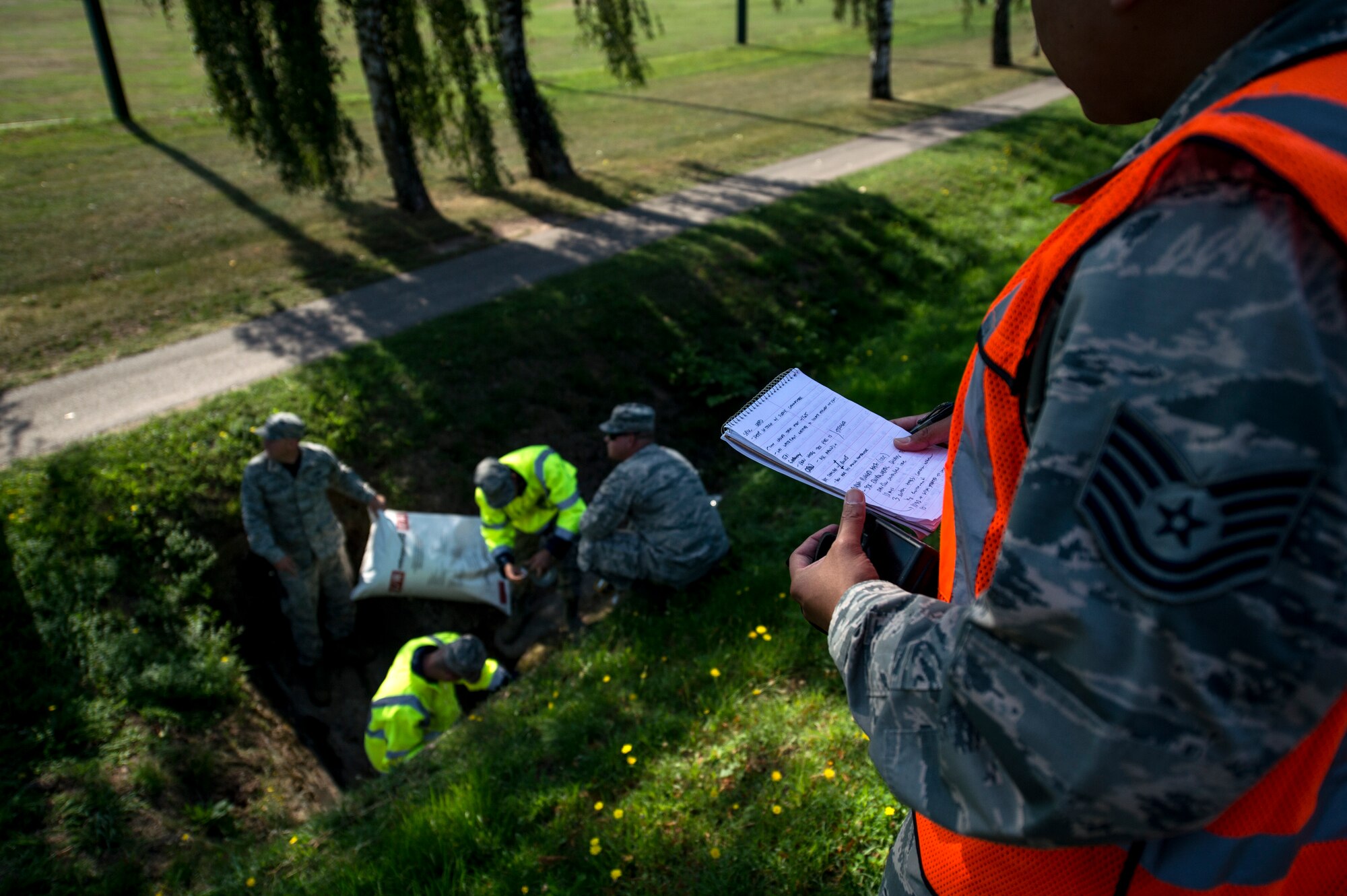 A member of the exercise evaluation team watches members of the 52nd Civil Engineer Squadron participate in a fuel spill exercise Aug. 7, 2015, at Spangdahlem Air Base, Germany. The exercise tested the abilities of the 52nd Fighter Wing to contain over 40,000 simulated gallons of spilt fuel. (U.S. Air Force photo by Senior Airman Rusty Frank/Released)