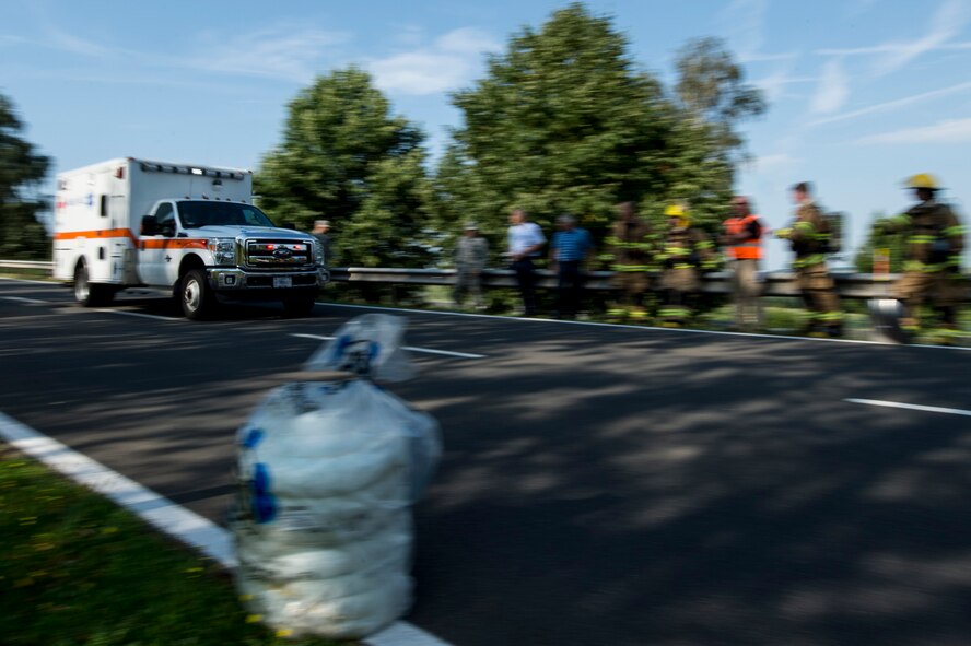 An ambulance drives past first responders during a fuel spill exercise Aug. 7, 2015, at Spangdahlem Air Base, Germany. The 52nd Medical Group demonstrated the unit's ability to execute the coordination of patient movement as one of their many objectives for the exercise. (U.S. Air Force photo by Senior Airman Rusty Frank/Released)