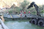 Members of the 132nd Multirole Bridge Company (MRBC), California Army National Guard, maneuver a bay across the Cache Creek River Aug. 7, 2015 in Yolo County, California. The California National Guardsmen were called upon to upstage a floating bridge in the Cache Creek National Park to allow CAL FIRE easier access to battle the Rocky Fire.
