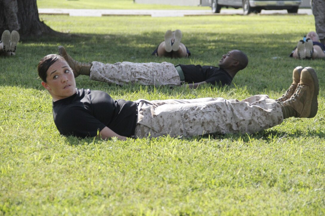 Sgt. Sonya L. Schmidt and Staff Sgt. Norris L. Russell Jr., Marine Corps Recruiting Station Kansas City recruiters, keep their feet up during a rest period of flutter kicks between demonstrations of the Marine Corps Martial Arts Program during RS Kansas City's all-female pool function aboard Camp Clark in Nevada, Mo., Aug. 7, 2015. 