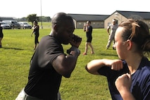 Staff Sergeant Norris L. Russell Jr., a Marine Corps Recruiting Station Kansas City recruiter, demonstrates a proper horizontal elbow strike to a poolee during RS Kansas City's all-hands female pool function at Camp Clark in Nevada, Mo., Aug. 7, 2015. 