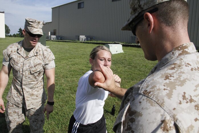 Gunnery Sergeant Nicholas McCulloch, a Marine Corps Recruiting Station Kansas City recruiter, instructs a poolee to strike his hand with a horizontal elbow strike as Staff Sgt. Adam Halter, a RS Kansas City recruiter, looks on and critiques during RS Kansas City's all-hands female pool function at Camp Clark in Nevada, Mo., Aug. 7, 2015. 