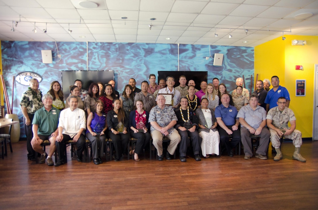 Special guests and Marine Corps Community Services Hawaii staff pose for a photo after an awards presentation at Kahuna’s Sports Bar and Grill, Aug. 6, 2015. Col. Sean C. Killeen, the commanding officer of Marine Corps Base Hawaii, presented 2014 Food and Hospitality Excellence Awards to representatives from 13 MCCS Hawaii services. More than 60 facilities across the Corps sent nominations to Headquarters Marine Corps for the excellence awards. MCB Hawaii nominated and was awarded for all 13 services. In addition, Kahuna’s was named Club of the Year for 2014, and Camp H.M. Smith’s Aloha Kitchen was given “Honorable Mention” as the runner up for Food and Beverage Facility of the Year. Providing excellent service is the mission of MCCS, which directly supports units, individuals and families in order to enhance and sustain combat readiness for all operating forces and tenant organizations aboard the installation. (U.S. Marine Corps photo by Kristen Wong/Released)