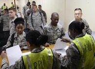 U.S. Air Force Airmen go through a reception processing unit as part of a Mission Focused Exercise on Kadena Air Base, Japan, Aug. 5, 2015. Representatives from various base agencies provided booths for mock-deployers in order to quickly and effectively prepare them for their simulated assignments. MFEs are designed to simulate contingency operations taken from one or more of the wing's mission sets such as forward power projection with the purpose of polishing procedures and demonstrating capabilities. (U.S. Air Force photo by Airman 1st Class John Linzmeier)