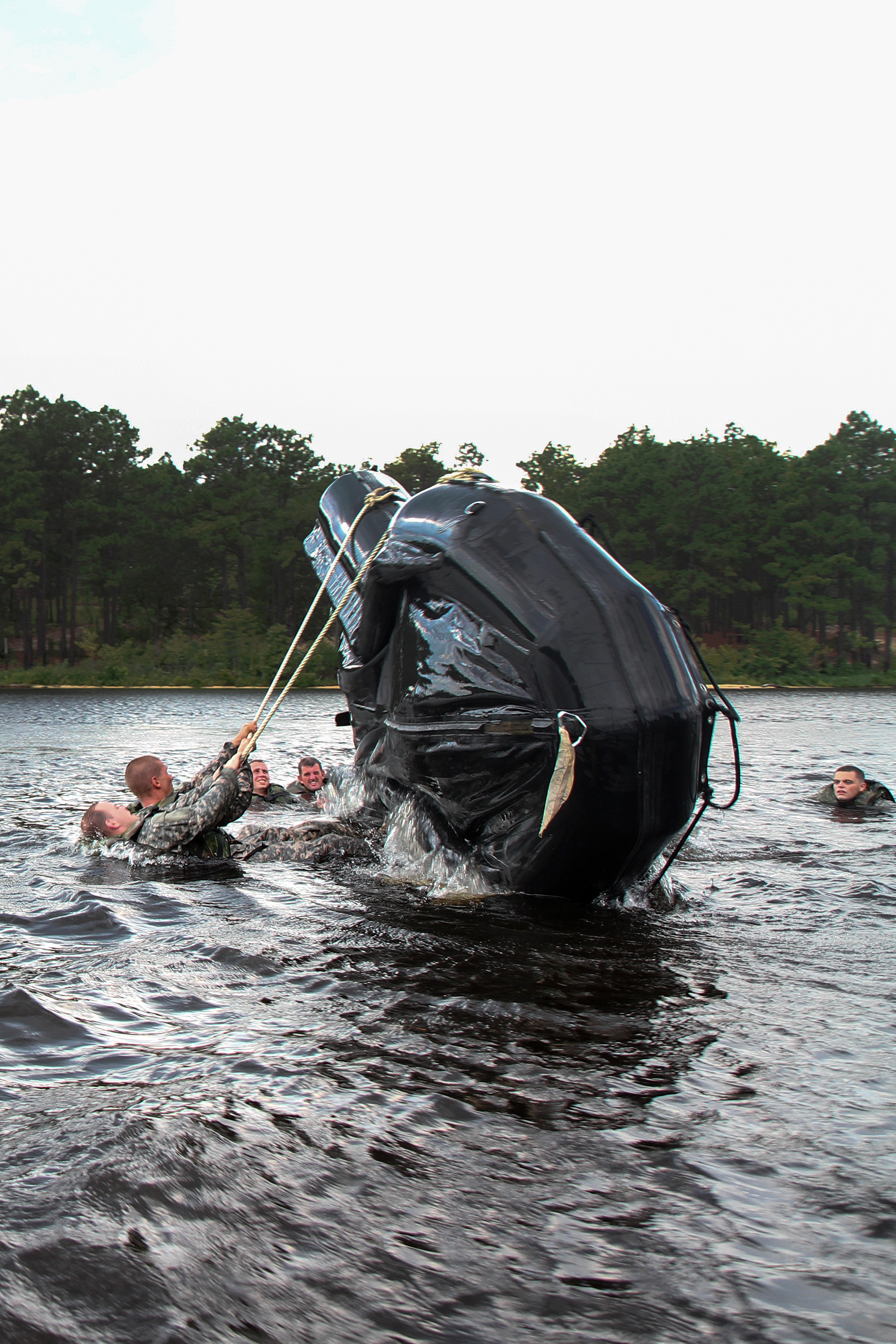 Paratroopers use ropes to capsize a Zodiac boat in Mott Lake on Fort