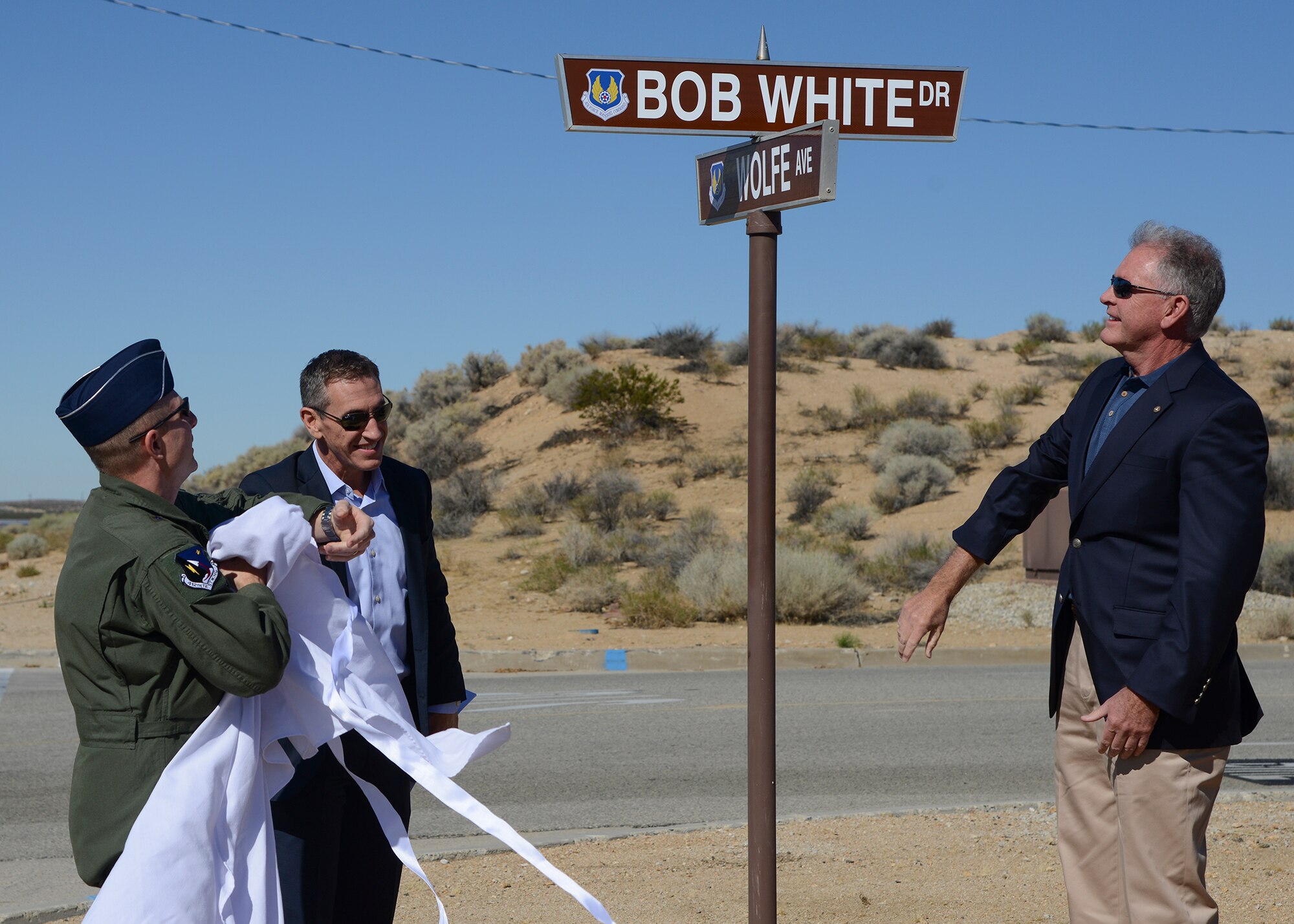 From left to right: Brig. Gen. Carl Schaefer, 412th Test Wing commander, along with Dennis and Greg White, unveil the newly named Bob White Drive Aug. 7. The street is named after Dennis and Greg's father who was both a record-breaking test pilot and fighter pilot hero who served in three wars. (U.S. Air Force photo by Rebecca Amber)