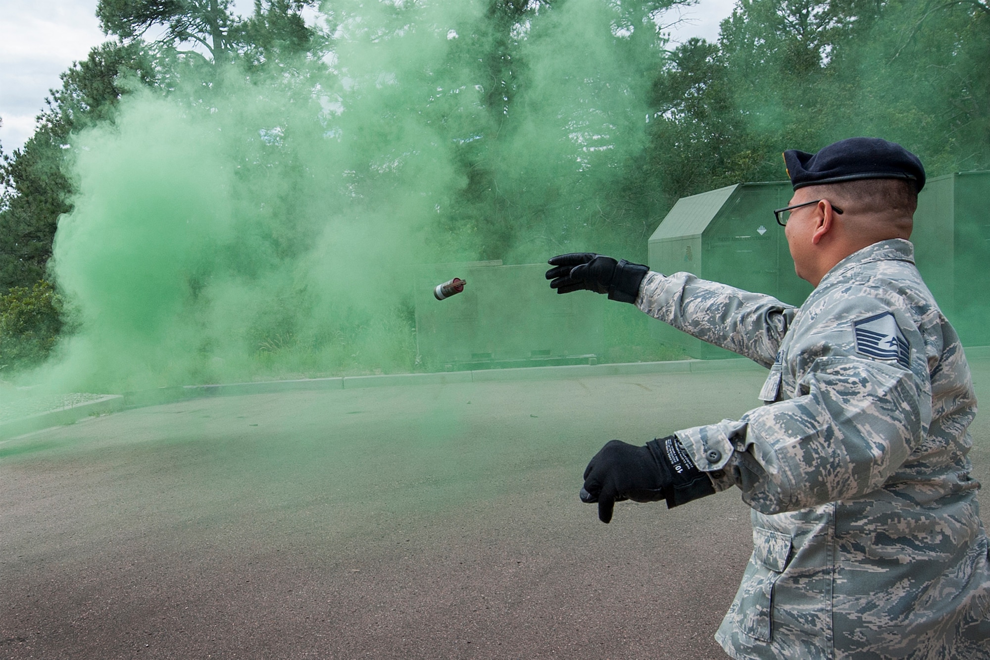 PETERSON AIR FORCE BASE, Colo. - Master Sgt. Crisanto Quinto, 721st Security Forces Squadron, noncommissioned officer in charge of training, pulls the pin and throws an M18 Smoke Grenade on Aug. 3, 2015 at Cheyenne Mountain Air Force Station.  Once activated, the grenade produces a cloud of colored smoke for approximately 90 seconds. (Photo by Craig Denton)
