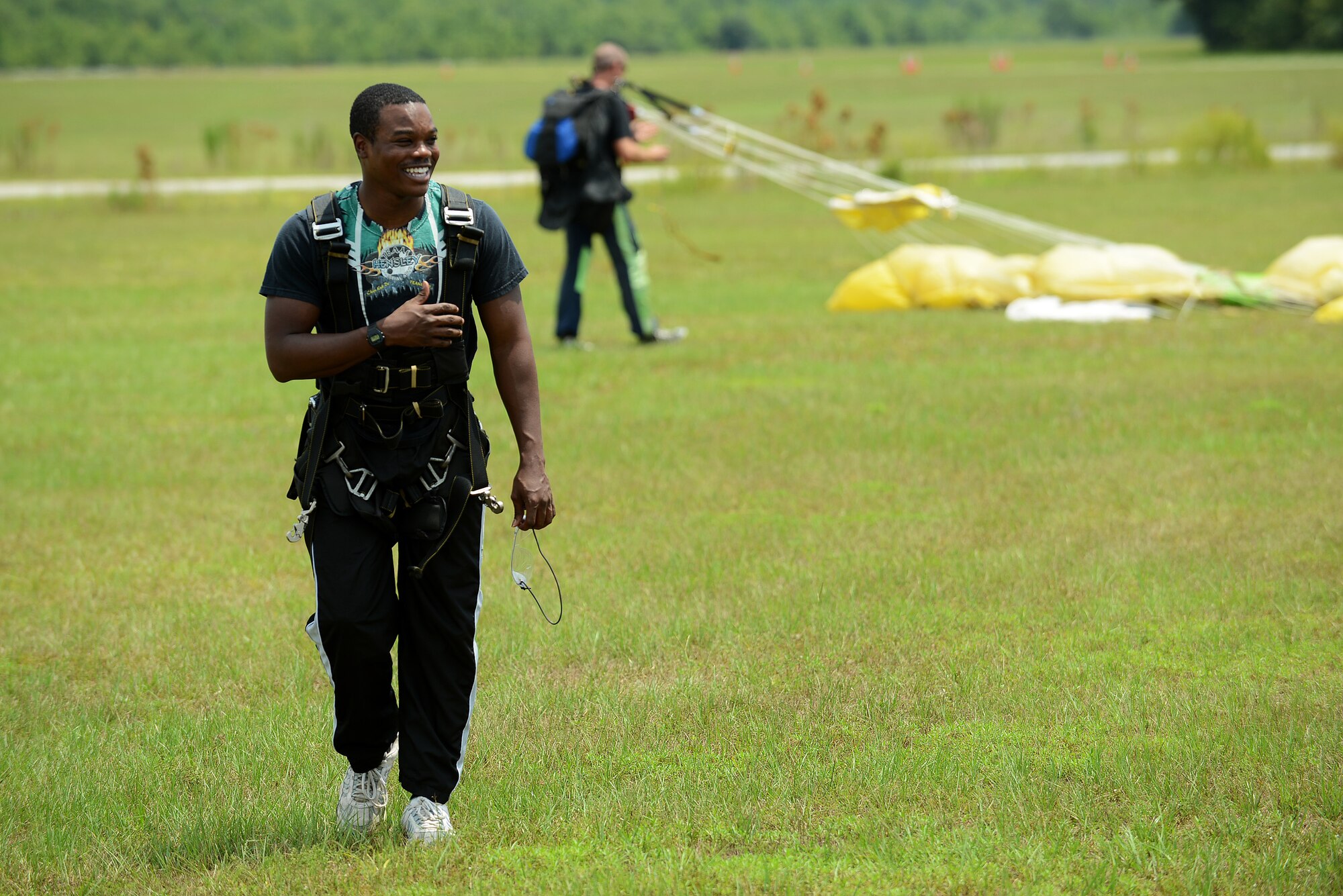 U.S. Air Force Airman 1st Class Alex Gardner, 20th Operations Support Squadron knowledge manager, walks back to the hanger after jumping out of an airplane during a 20th Force Support Squadron skydiving event at Walterboro, S.C., Aug. 1, 2015. Team Shaw members jumped out of the airplane tandem with an instructor and freefell for approximately 30 seconds before pulling the rip cord activating the parachute and floating safely to ground (U.S. Air Force photo by Senior Airman Michael Cossaboom/Released)