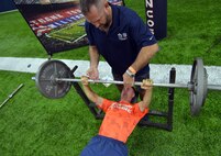 K.C. Jones, former center for the Denver Broncos, spots 1st Lt. Matthew Neeld, 22nd Space Operations Squadron crew commander, during in the bench press event at the Denver Broncos Military Combine Friday, August 7, 2015, at the Dove Valley Fieldhouse in Englewood, Colorado. The bench press was one of five events in which participants showcased their abilities. (U.S. Air Force photo/Staff Sgt. Debbie Lockhart)