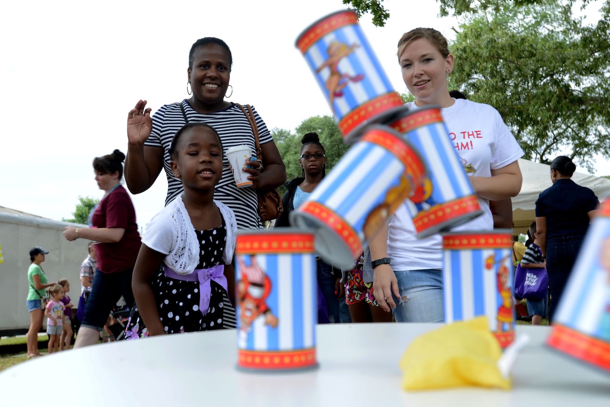 A Team Shaw child throws a bean bag at a stack of cans during the End of Summer Reading Program Carnival in front of the McElveen Information and Learning Center at Shaw Air Force Base, S.C., Aug. 8, 2015. The program set goals for children to reach, such as 1,120 reading minutes for their first goal, in order to win prizes. (U.S. Air Force photo by Airman 1st Class Kelsey Tucker/Released)