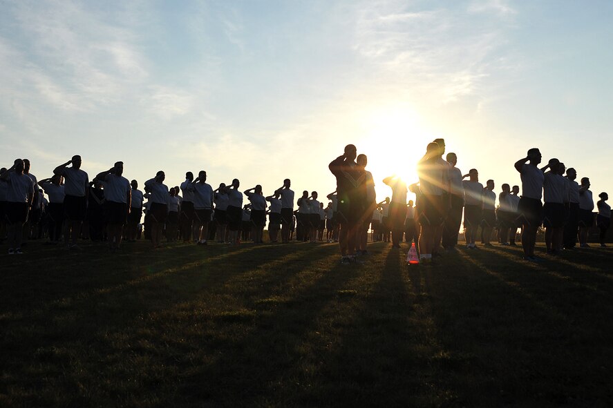 Airmen pause to render courtesies for morning reveille during the warm-up session before a wing run on Grand Forks Air Force Base, N.D., Aug. 6, 2015. The run was two miles long and promoted camaraderie amongst all squadrons of the base. (U.S. Air Force photo by Airman 1st Class Bonnie Grantham/Released)
