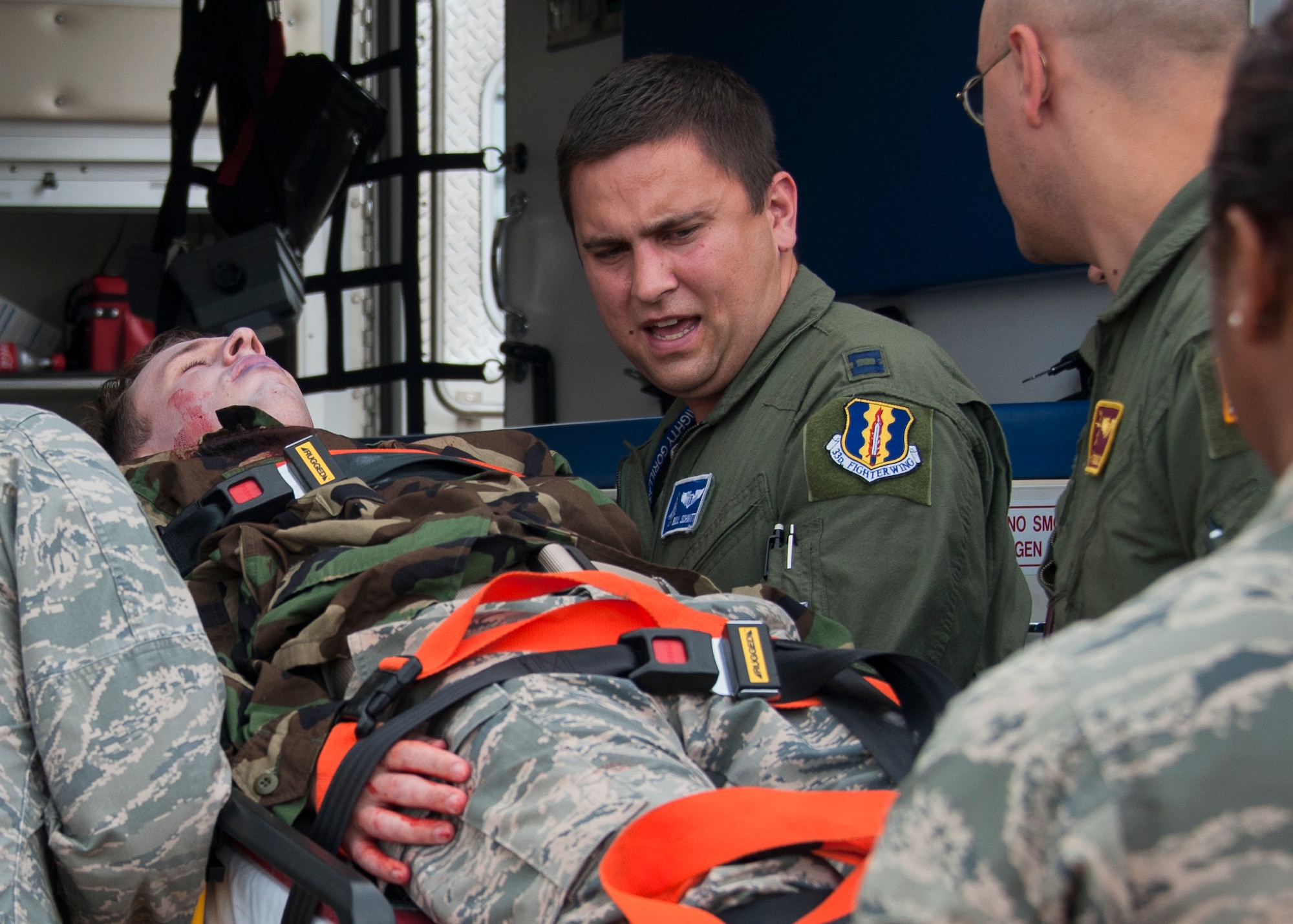 Capt. Edward Schmitt, 33rd Fighter Wing, helps lift an injured Airman into an ambulance for treatment during a simulated aircraft hijacking scenario as part of the 96th Test Wing’s force protection condition exercise Aug. 6 at Eglin Air Force Base, Fla.  The FPCON exercise tested the base’s first responders’ rescue skills while the simulated hijacker was apprehended and the injured were moved to safety for treatment. (U.S. Air Force photo/Ilka Cole)