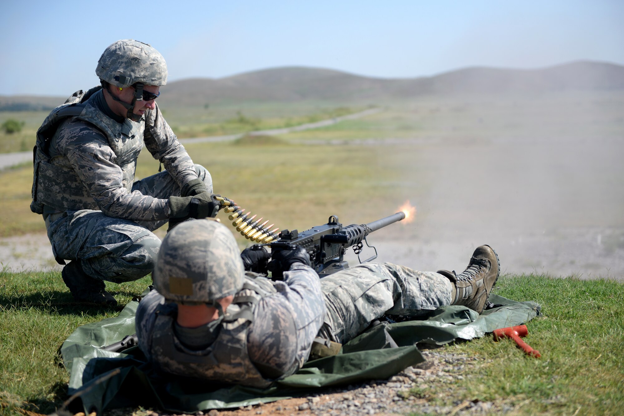 FORT SILL, Okla. – U.S. Air Force Staff Sgt. Joseph Sewell, 97th Security Forces Squadron, combat arms training and maintenance instructor, fires an M2 machine gun while U.S. Air Force Senior Airman Bradley Primmer, 82nd SFS CATM instructor from Sheppard Air Force Base, Texas, feeds munitions to the weapon at the Kerr Hill Machine Gun Range, Aug. 7, 2015. Members from the 97th SFS and 82nd SFS trained together to qualify and maintain M2 certifications. (U.S. Air Force photo by Senior Airman Dillon Davis/Released)