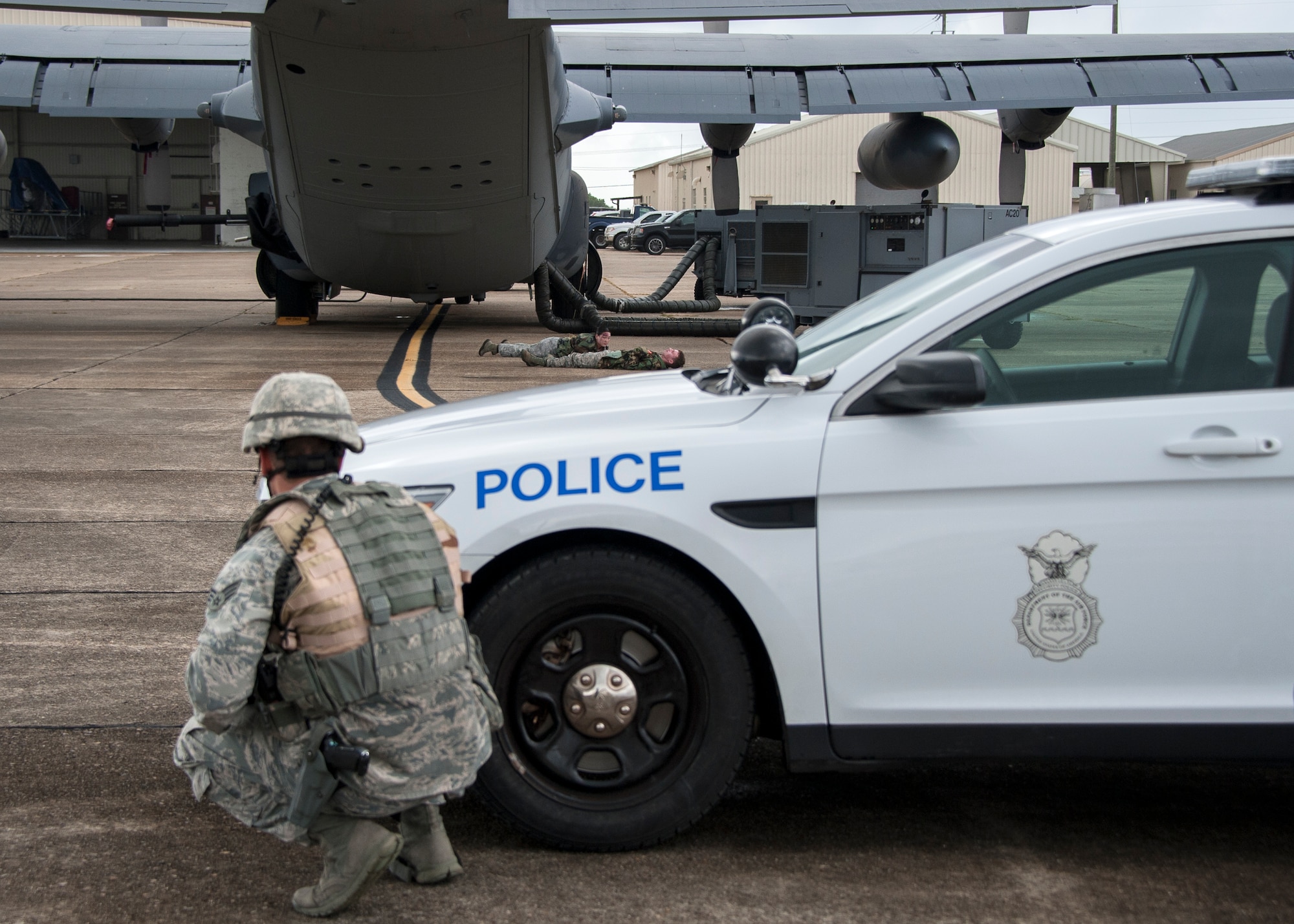 Senior Airman Nathan Koenig, 96th Security Forces Squadron, crouches behind his patrol car during a simulated aircraft hijacking scenario as part of the 96th Test Wing’s force protection condition exercise Aug. 6 at Eglin Air Force Base, Fla. The FPCON exercise tested the base’s first responders’ rescue skills while the simulated hijacker was apprehended and the injured were moved to safety for treatment. (U.S. Air Force photo/Ilka Cole)