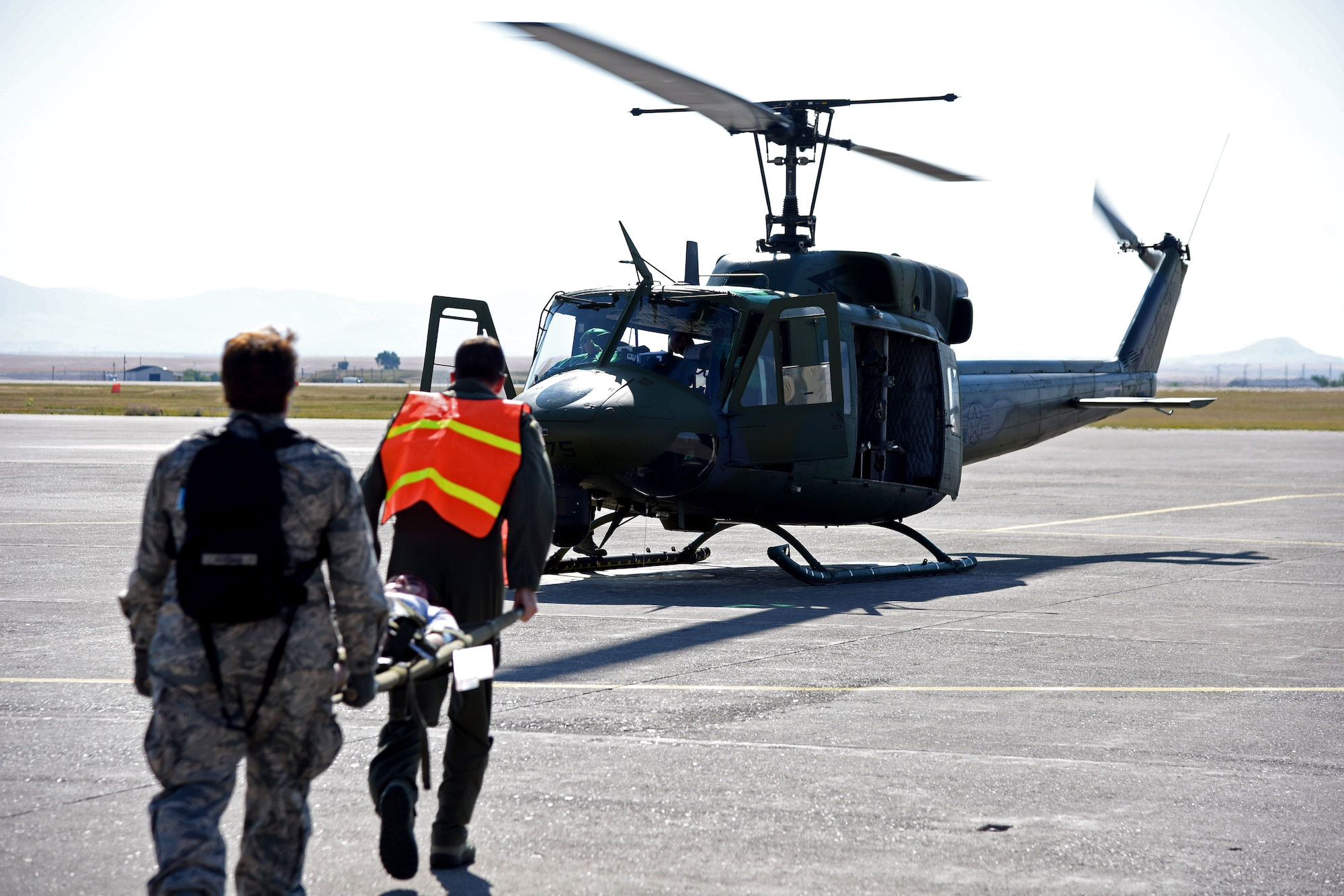 Airmen transport a simulated natural disaster victim to a UH-1N Huey helicopter on the flightline at Malmstrom Air Force Base, Mont., Aug. 10, 2015, as part of a Major Accident Response Exercise. Forty-two victims of a simulated building collapse were air lifted to a virtual triage center in downtown Great Falls and Helena, Mont., approximately 90 miles away. (U.S. Air Force photo/Airman 1st Class Collin Schmidt)