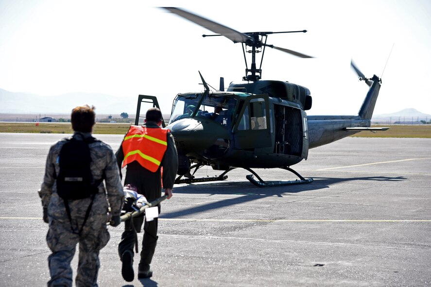 Airmen transport a simulated natural disaster victim to a UH-1N Huey helicopter on the flightline at Malmstrom Air Force Base, Mont., Aug. 10, 2015, as part of a Major Accident Response Exercise. Forty-two victims of a simulated building collapse were air lifted to a virtual triage center in downtown Great Falls and Helena, Mont., approximately 90 miles away. (U.S. Air Force photo/Airman 1st Class Collin Schmidt)