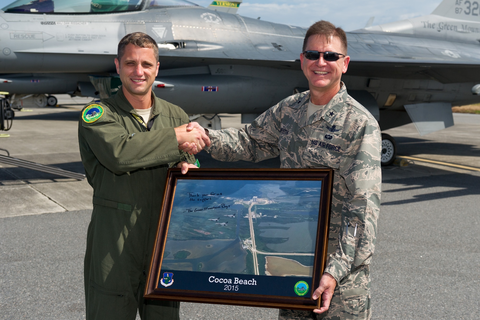 Brig. Gen. Wayne Monteith, 45th Space Wing commander, (right), shakes hands with Lt. Col. John Flint, Vermont Air National Guard (VTANG) F-16 pilot, as he receives a signed photo from members of the VTANG, Aug. 6, 2015, at the Skid Strip at Cape Canaveral Air Force Station, Fla. The VTANG used the airfield at the Cape for a base of operations during their Dissimilar Air Combat Training Exercise in order to train and hone their combat skills. (U.S. Air Force photo by Cory Long/Released) 