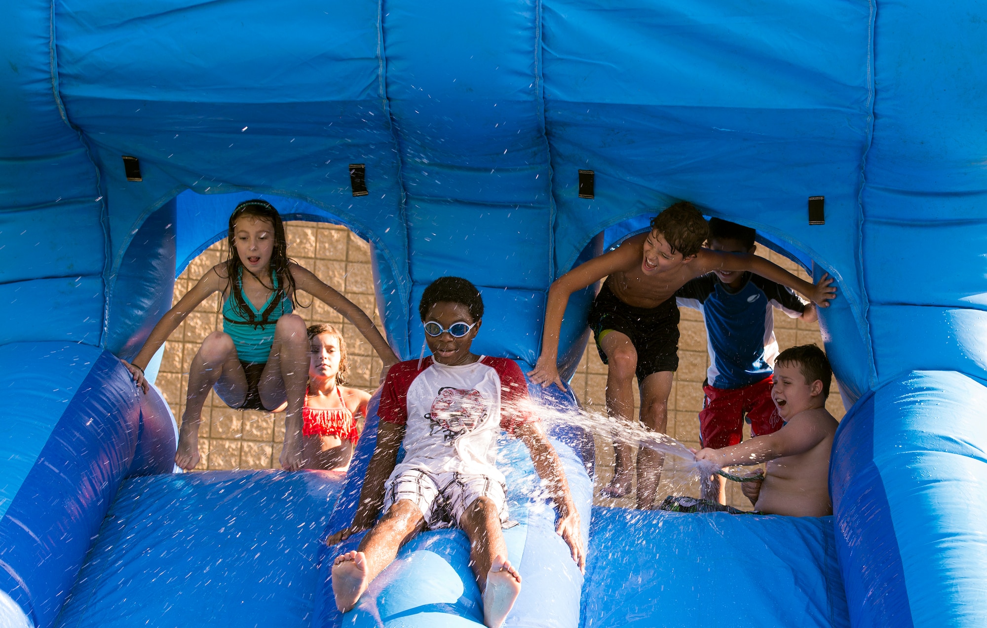 Moody’s Youth Programs students and friends play on a slip-and-slide bounce house during the Back to School Bash Aug. 8, 2015, at Moody Air Force Base, Ga. Approximately 20 participants were in attendance at the event. (U.S. Air Force photo by Airman Greg Nash/Released)