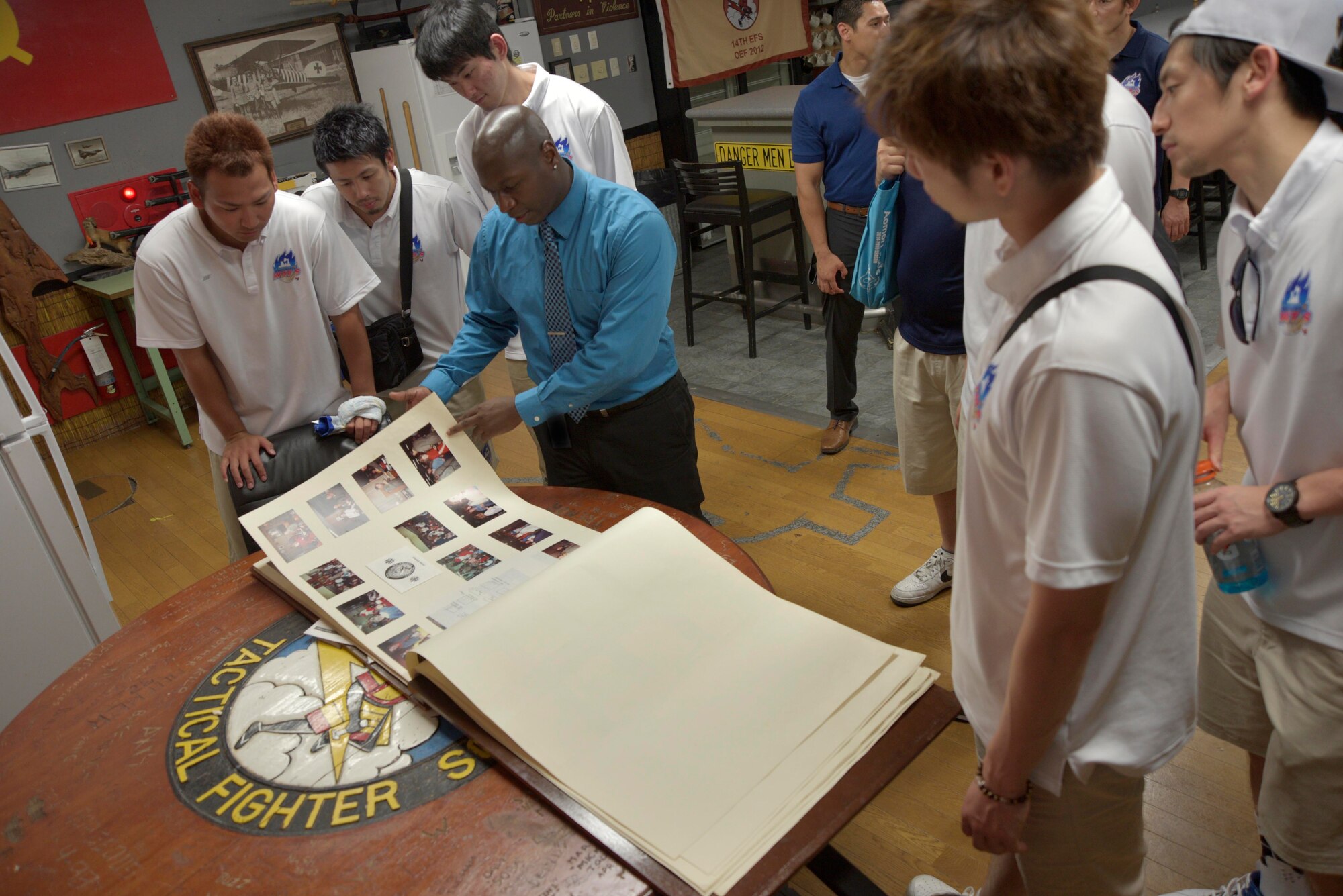 Eugene Scott, 35th Operations Group executive assistant, shares historical photos and imagery of the 14th Fighter Squadron with Aomori WATS basketball players at Misawa Air Base, Japan, Aug. 5, 2015. Scott showed the team photos and newspaper articles of historical 14 FS events dating back to the early 1980s. (U.S. Air Force photo by Senior Airman Jose L. Hernandez-Domitilo/Released)