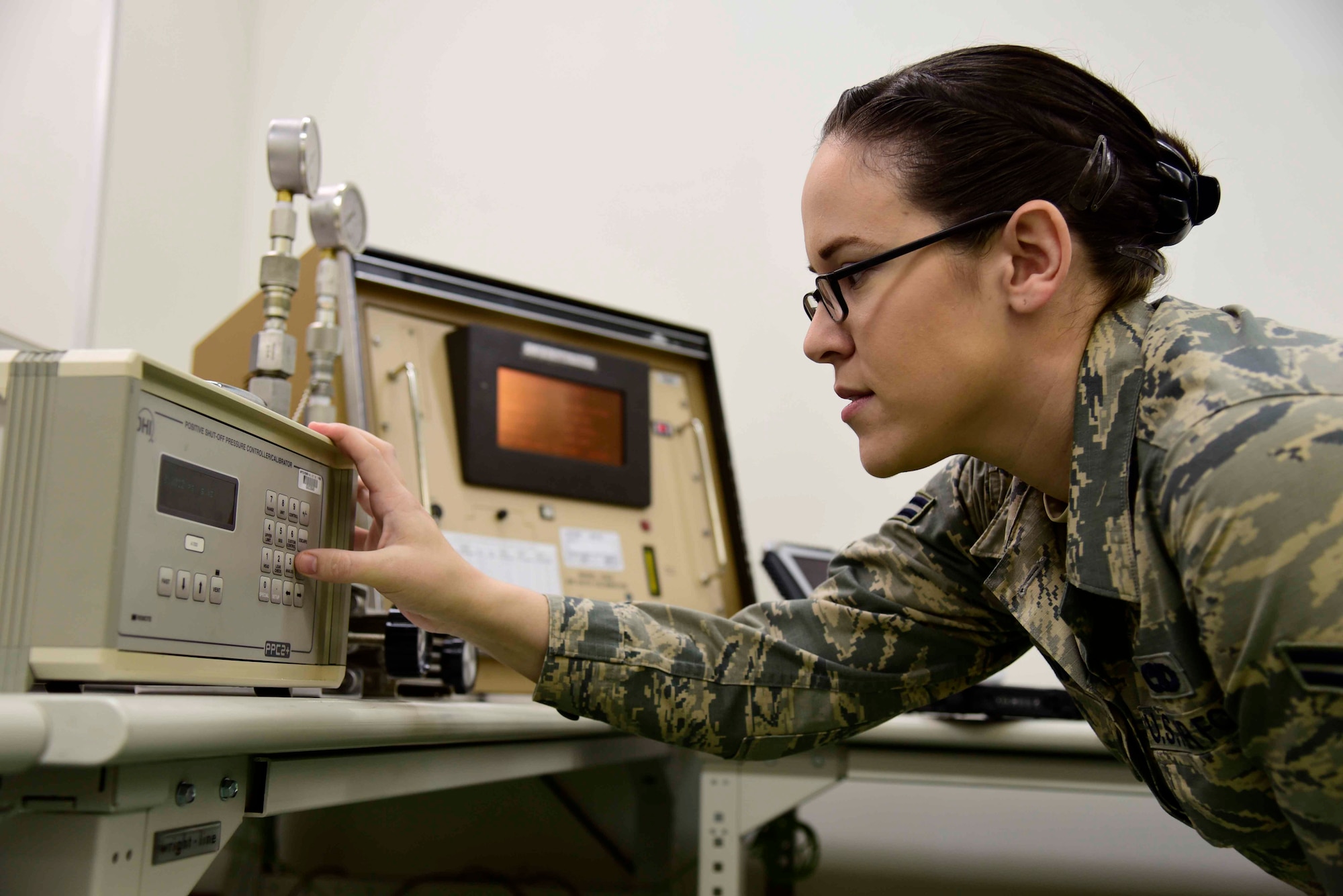 U.S. Air Force Airman 1st Class Emily New, 35th Maintenance Squadron precision measurement equipment laboratory journeyman, calibrates pressure gauges at Misawa Air Base, Japan, Aug. 6, 2015. She services equipment used to run tests on F-16 Fighting Falcon aircraft. (U.S. Air Force photo by Airman 1st Class Jordyn Fetter/Released)