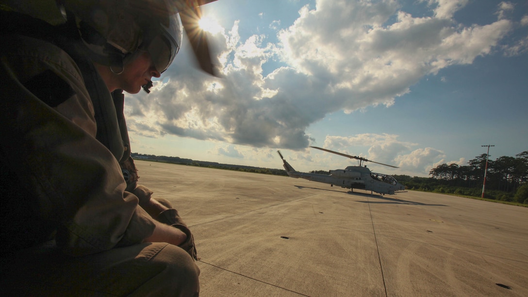 Sgt. Corey Burgess awaits take off across from an AH-1W Super Cobra during a training exercise testing a digital interoperability system at Marine Corps Air Station Cherry Point, N.C., July 24, 2015, Digital interoperability is the technology capable of increasing prowess on the battlefield. The exercise included Marine Light Attack Helicopter Squadron 467, Marine Unmanned Aerial Vehicle Squadron 2, and U.S. Marine Corps Forces, Special Operations Command, testing a LINK 16 conversion system for one of the first times within an explicitly rotary-wing exercise.  Burgess is a Bell UH-1 crew chief with HMLA-467.