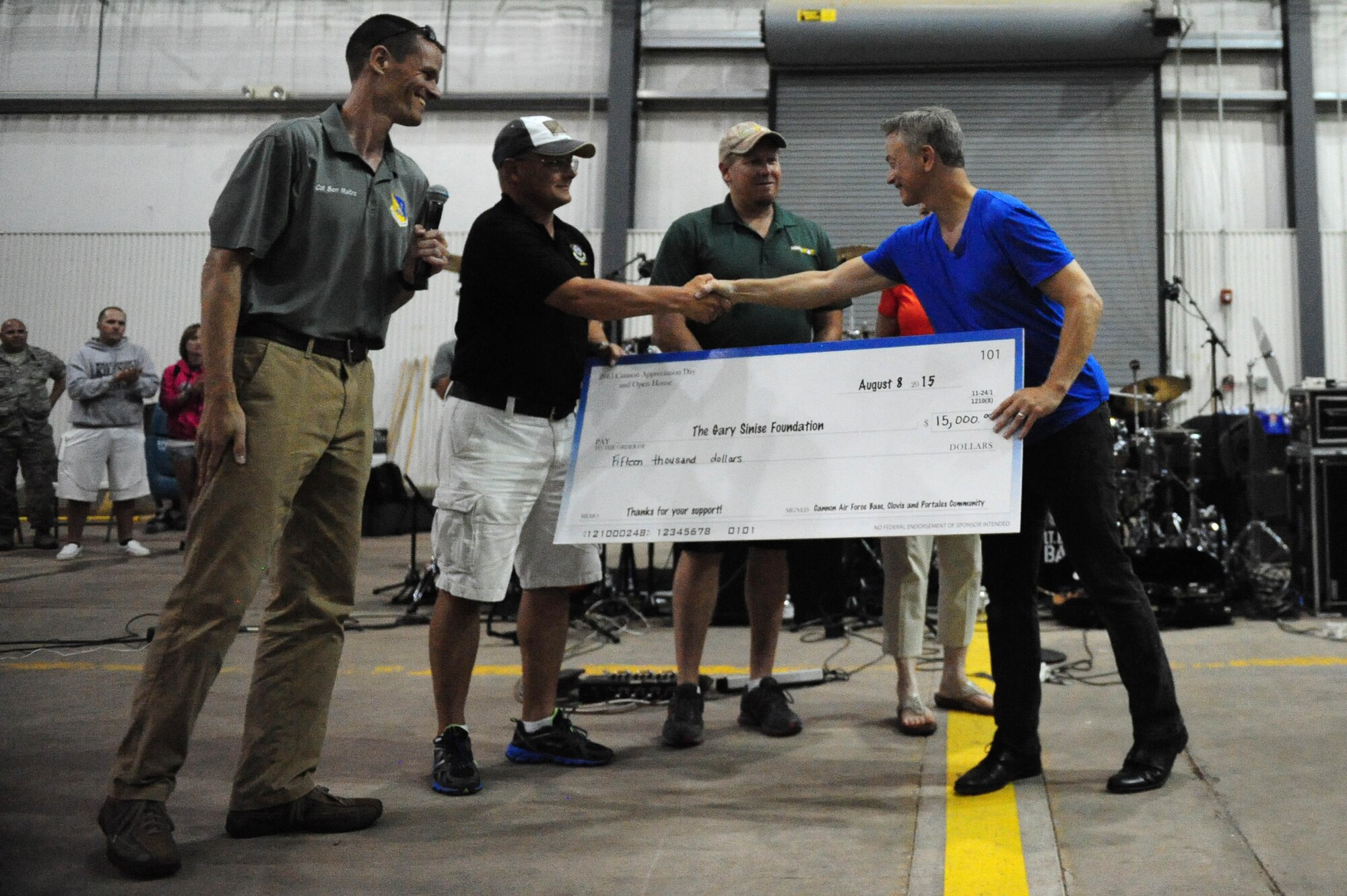 Community members, present a donation to Gary Sinise, founder of the Gary Sinise Foundation, during the closing remarks of the 2015 “Rockin’ the High Planes” Open House, Aug. 8, 2015 at Cannon Air Force Base, N.M. Members of the High Plains community worked together to raise money for the Gary Sinise Foundation.  (U.S. Air Force photo/Tech. Sgt. Manuel Martinez)