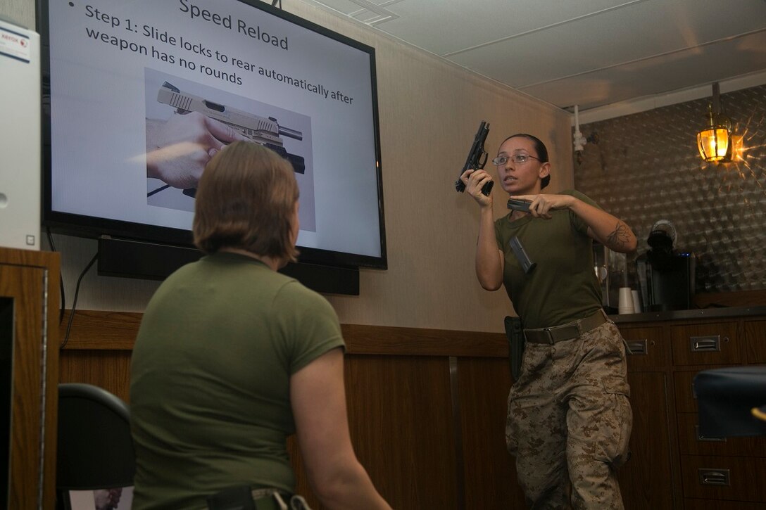 INDIAN OCEAN (July 23, 2015) U.S. Marine Lance Cpl. Chevon Ferrel, right, demonstrates a speed-reload with a M9 service pistol aboard the amphibious assault ship USS Essex (LHD 2). Ferrel is a member of the 15th Marine Expeditionary Unit’s Female Engagement Team and an ammunition technician specialist with Combat Logistics Battalion 15, 15th MEU. The FET taught pistol marksmanship to a group of inexperienced Marines to become more confident in their teaching skills. The 15th MEU is embarked on the Essex Amphibious Ready Group and deployed to maintain regional security in the U.S. 5th Fleet area of operations. (U.S. Marine Corps photo by Cpl. Anna Albrecht/Released)