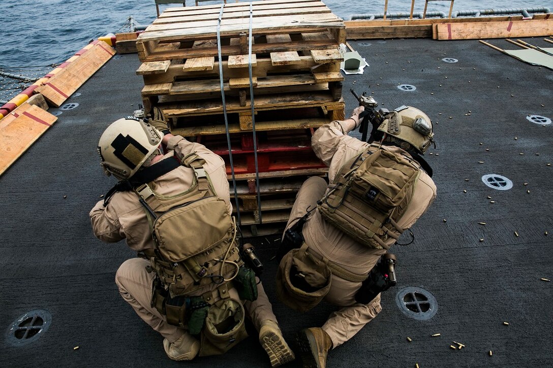 INDIAN OCEAN (Aug. 4, 2015) U.S. Marines with the 15th Marine Expeditionary Unit’s Maritime Raid Force fire at targets from behind a barricade during a deck shoot aboard the amphibious assault ship USS Essex (LHD 2). These Marines practiced maneuvering as buddy teams to different sources of cover to enhance their marksmanship skills. The 15th MEU is embarked on the Essex Amphibious Ready Group and deployed to maintain regional security in the U.S. 5th Fleet area of operations. (U.S. Marine Corps photo by Cpl. Anna Albrecht/Released)