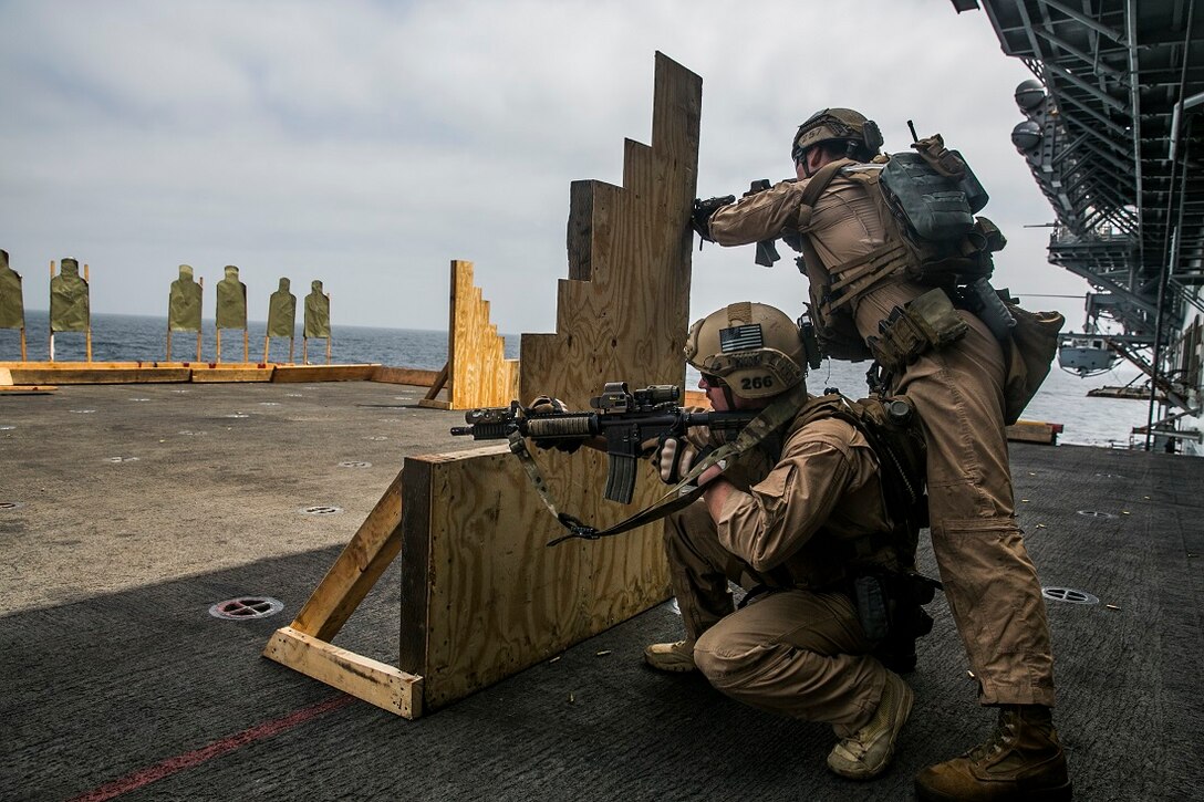 INDIAN OCEAN (Aug. 4, 2015) U.S. Marines with the 15th Marine Expeditionary Unit’s Maritime Raid Force fire at targets from behind a barricade during a deck shoot aboard the amphibious assault ship USS Essex (LHD 2). These Marines practiced maneuvering as buddy teams to different sources of cover to enhance their marksmanship skills. The 15th MEU is embarked on the Essex Amphibious Ready Group and deployed to maintain regional security in the U.S. 5th Fleet area of operations. (U.S. Marine Corps photo by Cpl. Anna Albrecht/Released)