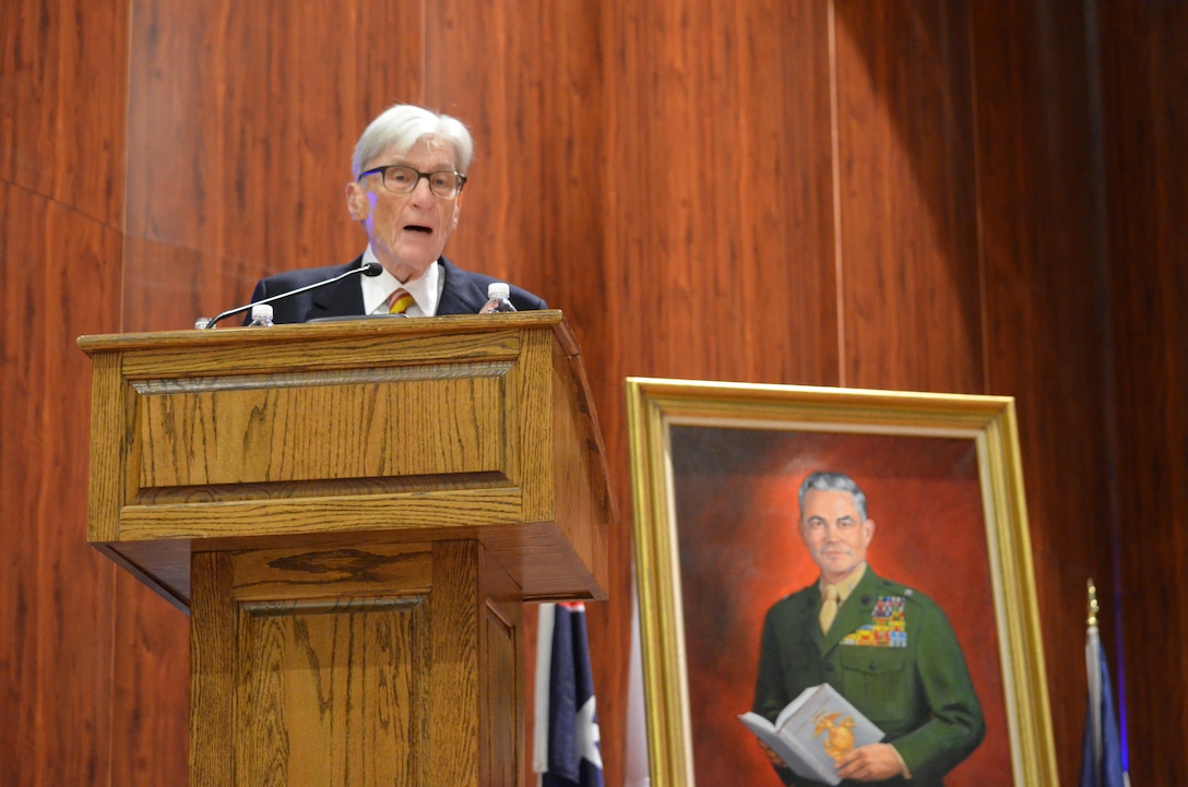 Sen. John Warner speaks to an audience of Marine Corps University students and staff, and distinguished guests during an Aug. 7 ceremony dedicating the new MCU building in his name. Behind him is a new portrait of Brig. Gen. Edwin Simmons that will hang in the Brigadier General Edwin H. Simmons Marine Corps History Center.