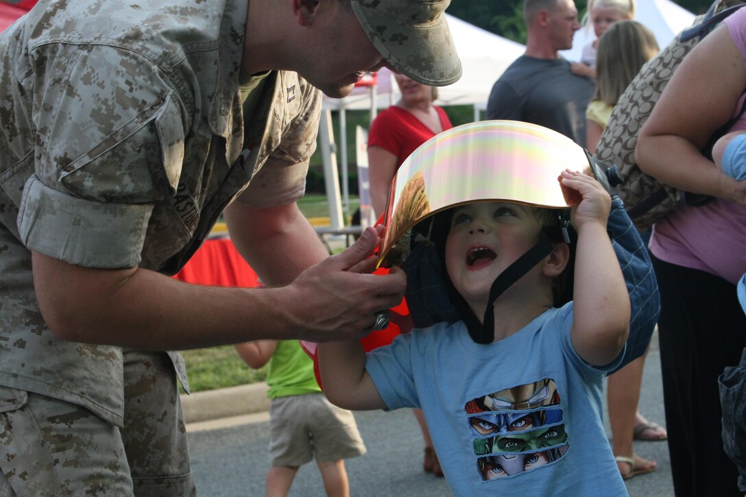 A future firefighter tries on his first helmet at the National Night Out aboard Marine Corps Base Quantico. The National Night Out was hosted by Security Battalion on Aug. 4 in front of the Lincoln Military Housing office.  There were static displays and demonstrations from military police and firefighters. The National Night Out is a community initiative intended to better acquaint communities with their first responders. Nationally, the initiative is in its 32nd year.