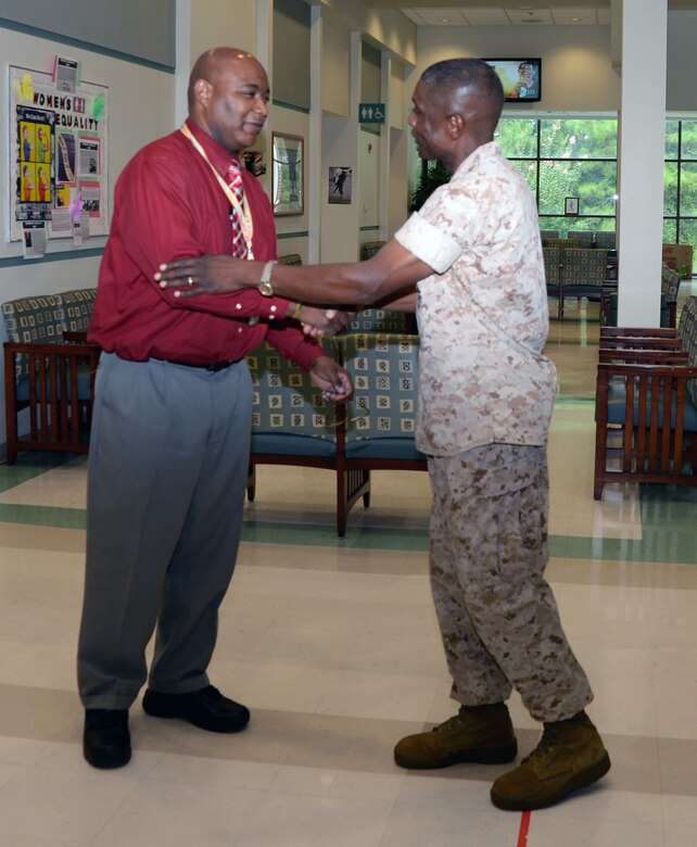 Col. James C. Carroll III, commanding officer, Marine Corps Logistics Base Albany, presents a coin to Vincent Hairston, medical support assistant, Veterans Affairs Community-Based Outpatient Clinic, in the clinic housed aboard MCLB Albany, Aug. 7. Hairston provided outstanding customer service to a veteran in need of around-the-clock care. 