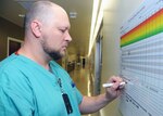 Keith Thompson, a critical care nurse at the U.S. Army Institute of Surgical Research Burn Center at Fort Sam Houston, writes a note on the Team View poster used as a communication tool at the Burn Intensive Care Unit.
