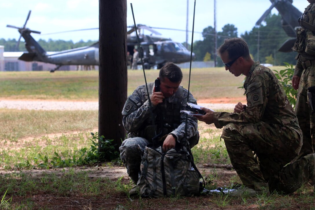 Army Chief Warrant Officer 2 Wozniaka, left, coordinates with an Army pathfinder assigned to ensure the correct frequency channels are set in order to communication during Operation Red Fury on Fort Bragg, N.C., Aug. 4, 2015. Wozniaka is a pilot assigned to the 82nd Airborne Division's 3rd General Support Aviation Battalion, 82nd Combat Aviation Brigade.