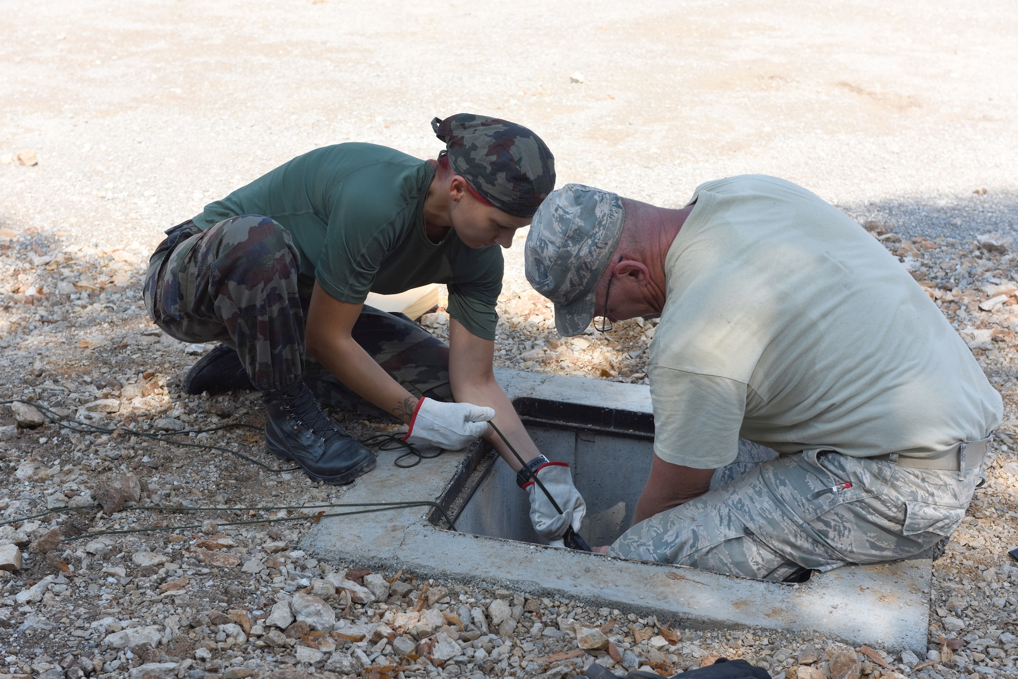 Slovene Pvt. Budefeld Adrijala and U.S. Air Force Master Sgt. Kelly Stewart, 140th Civil Engineer Squadron, Colorado Air National Guard (COANG), work together to attach pulls to a main power cable at Pocek Range, near Postonja, Slovenia, July 22, 2015. The SAF provided troops to assist Colorado Guardsmen restoring a historically old barn into a usable range facility to be used by SAF and NATO countries for joint, multinational training and exercises. (U.S. Air National Guard photo by Senior Airman Michelle Y. Alvarez-Rea/Released)