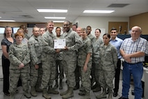 Airman 1st Class Jonathon Wright, center, 47th Communications Squadron cyber operations apprentice, poses with Col. Thomas Shank, 47th Flying Training Wing commander, and Chief Master Sgt. Teresa Clapper, 47th FTW command chief, after accepting the “XLer of the Week” award, here, August 6, 2015. The “XLer” is a weekly award chosen by wing leadership and is presented to those who consistently make outstanding contributions to their unit and Laughlin. (U.S. Air Force photo by Airman 1st Class Brandon May) (Released)