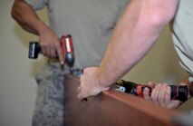 Airmen from the 22nd Civil Engineer Squadron screw hinges on a door Aug. 11, 2015, at McConnell Air Force Base, Kan. The doors were installed in Bldg. 1219, which is set to become the new alert facility. (U.S. Air Force photo by Senior Airman Colby L. Hardin)